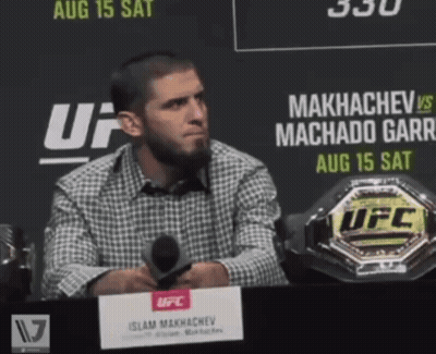 Man at Table With Microphone in Front of UFC Sign