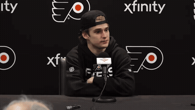 Man At Table With Microphone In Front Of Xfinity Sign GIF