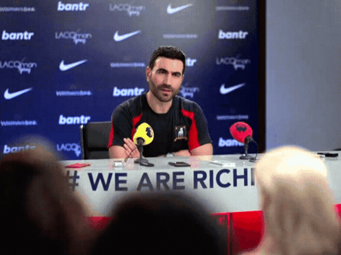 Man At Table With Sign We Are Richi GIF