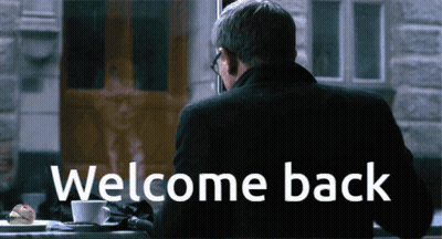 Man At Table With Welcome Back Sign GIF