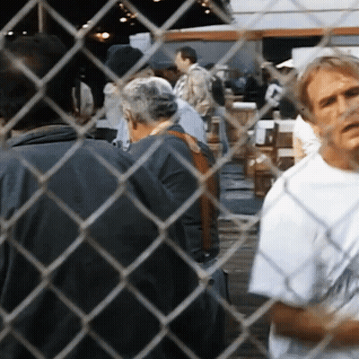 Man Behind Chain Link Fence Looking At Group GIF