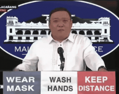Man Behind Podium Saying Wear Mask Wash Hands Keep Distance GIF