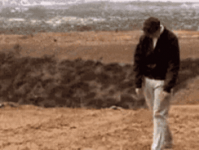 Man Black Jacket White Pants Walking Dirt Field GIF
