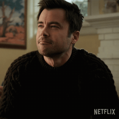 Man by Fireplace in Black Sweater Netflix Logo
