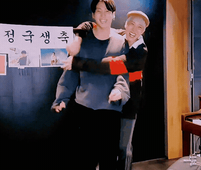 Man Carrying Another Man In Front Of Korean Sign GIF