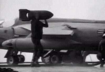 Man Carrying Large Bomb In Front Of Jet GIF