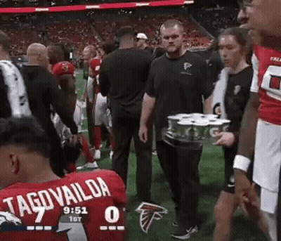 Man Carrying Tray of Cans on Field