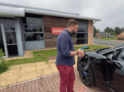 Man Charging Car In Front Of Elmt Building GIF