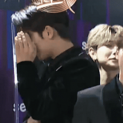 Man Covering Face In Front Of Crowd GIF