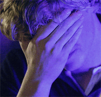 Man Covering Face With Hand In Front Of Blue Light GIF