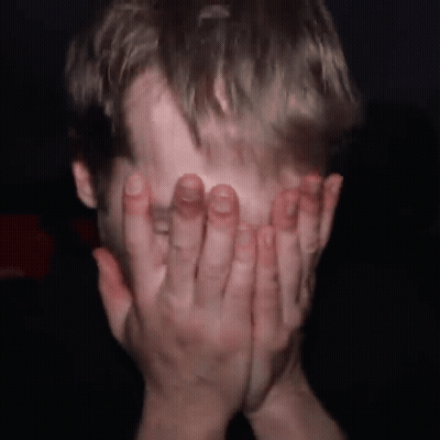 Man Covering Face With Hands In Dark Room GIF