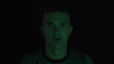 Man Covering Mouth In Dark Room With Green Light GIF