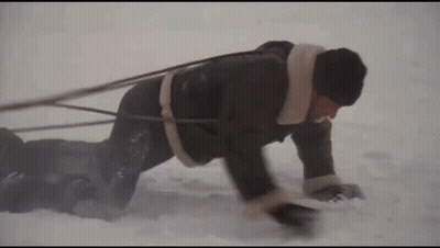 Man Crawling Through Snow Pulling Another Man On Sled GIF