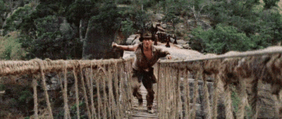 Man Crossing Rope Bridge In Woods GIF