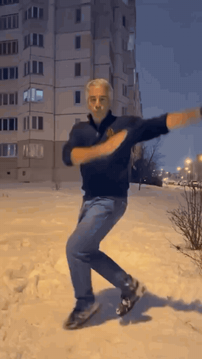 Man Dancing In Snow By Tall Building GIF