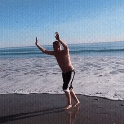 Man Dancing On Beach Arms Outstretched GIF