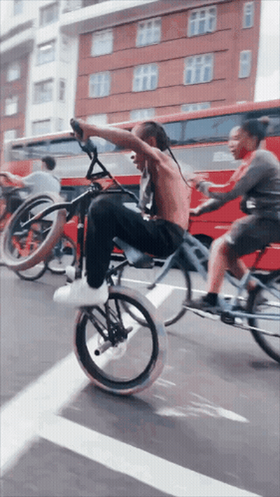 Man Doing Bike Trick With Woman Riding Behind GIF