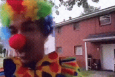 Man Dressed As Clown In Front Of Red House GIF