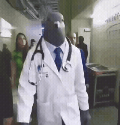 Man Dressed As Doctor With Stethoscope Walking Through Hallway GIF