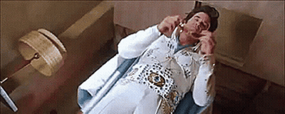 Man Dressed As Elvis Presley Laying On Bed Talking On Phone GIF