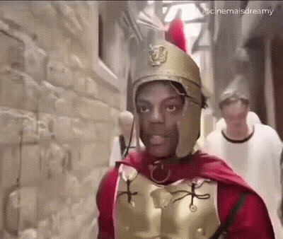 Man Dressed As Roman Soldier Walking Down Alley GIF