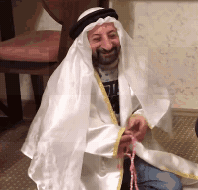 Man Dressed As Sheikh Holding Rosary And Smiling GIF