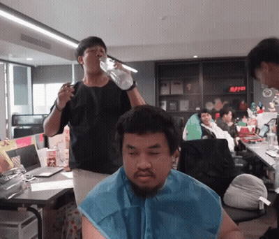 Man Drinking From Bottle While Another Shaves His Head GIF