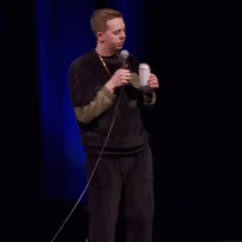 Man Drinking From Can On Stage Holding Microphone GIF