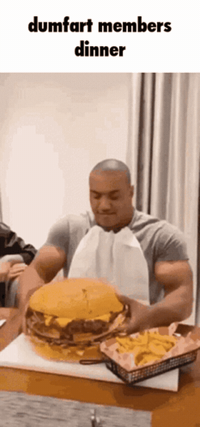 Man Eating Large Hamburger At Table GIF