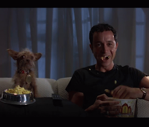Man Eating Popcorn While Small Dog Watches GIF
