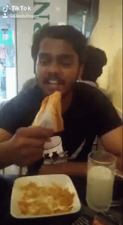 Man Eating Sandwich and Drinking Milk at Restaurant