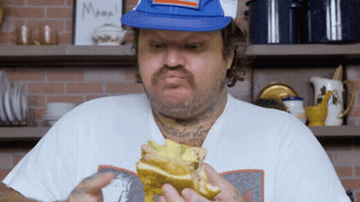 Man Eating Sandwich In Front Of Mama Sign GIF