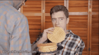 Man Eating Waffle While Another Holds Pancakes GIF