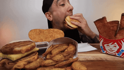 Man Eating Wendy's Sandwich Next To French Fries GIF