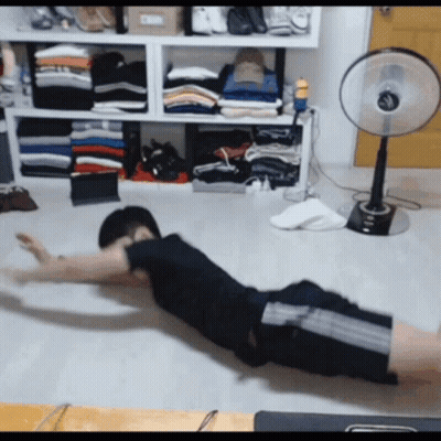 Man Exercising On Floor In Front Of Fan And Clothes GIF