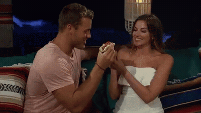 Man Feeding Hot Dog to Woman on Couch