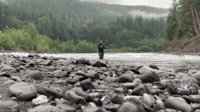 Man Fishing In River Surrounded By Rocks And Trees GIF