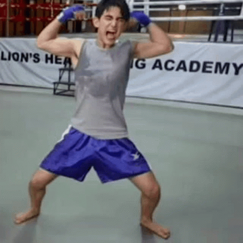Man Flexing Muscles In Boxing Ring With Blue Shorts GIF
