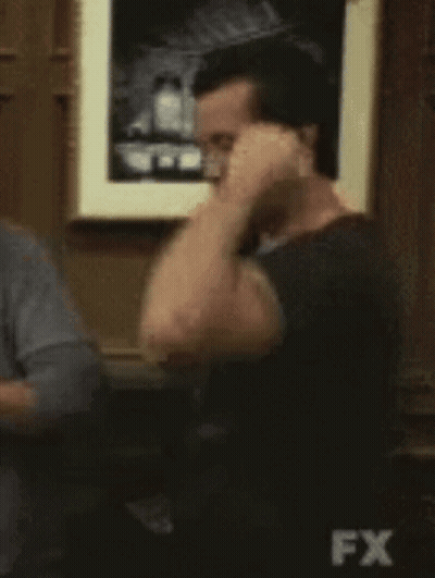 Man Flexing Muscles In Front Of FX Sign GIF