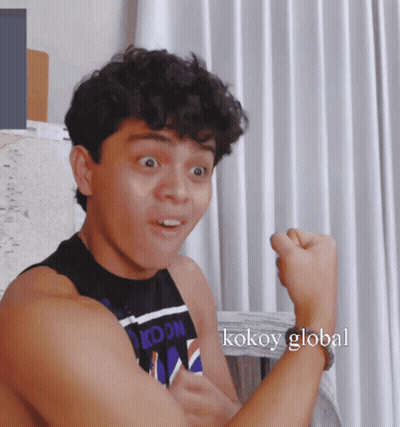 Man Flexing Muscles In Front Of Kokoy Global Curtain GIF