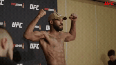 Man Flexing Muscles In Front Of UFC Sign GIF