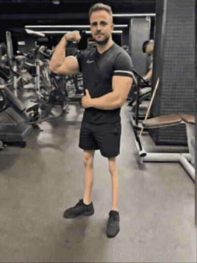 Man Flexing Muscles In Gym While Wearing Shorts GIF