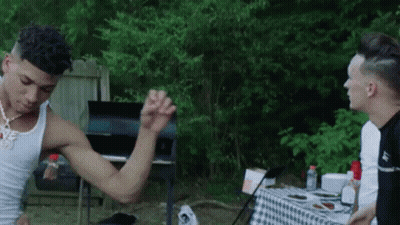 Man Flexing Muscles Next To Checkered Table GIF