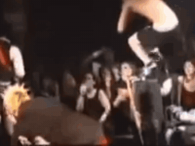 Man Flying Through Air Playing Guitar On Stage GIF
