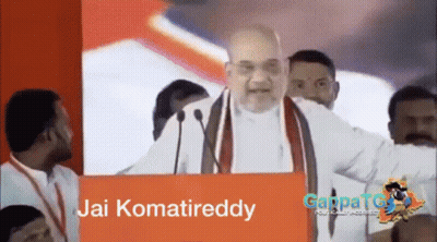 Man Giving Speech In Front Of Jai Komatreddy Sign GIF