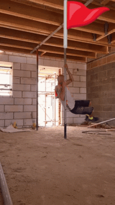 Man Hanging Upside Down On Pole With Red Flag GIF