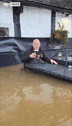 Man Having Drinks In The Middle Of Flooding GIF