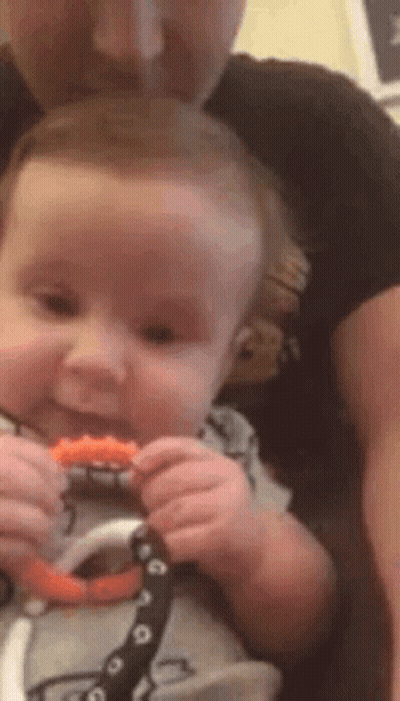 Man Holding Baby Chewing Teething Toy GIF