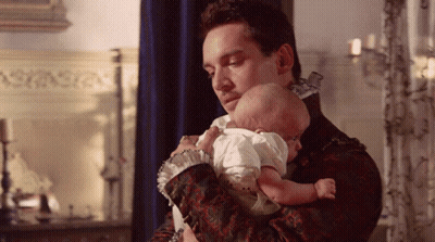 Man Holding Baby In Front Of Candles GIF