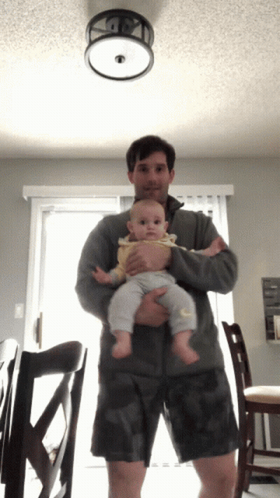 Man Holding Baby In Front Of Ceiling Light GIF